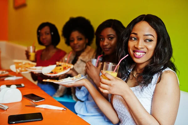 Quatro jovens meninas africanas em restaurante colorido brilhante com pizza — Fotografia de Stock