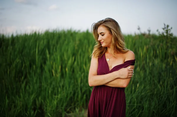 Blonde sensual woman in red marsala dress posing in the reeds. — Stock Photo, Image