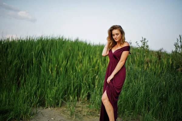 금발의 관능적 인 여자 에 빨간 마르살라 드레스 포즈 에 이 갈대. — 스톡 사진