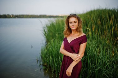 Kırmızı marsala elbise sarışın şehvetli kadın göl wi karşı poz