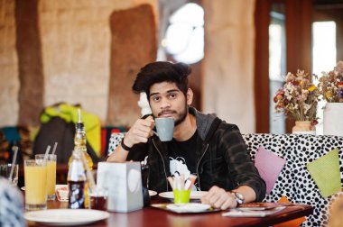 Rahat giyim sakal asyalı adam kapalı kafe ve içki cof oturan