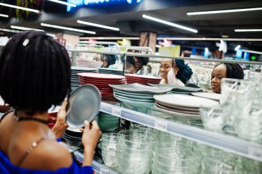 Afrikalı kadın grubu süpermarket raflarında renkli plakalar bakmak