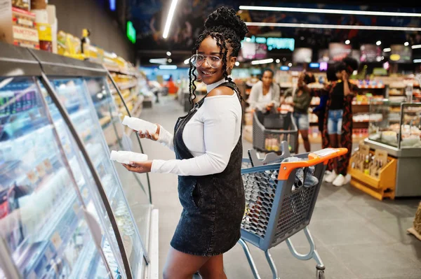 Африканський жінка з кошиком покупок виберіть пляшку йогурту з fridg — стокове фото