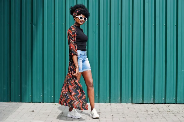 Африканская женщина с африканскими волосами, в джинсовых шортах и в белых солнцезащитных очках — стоковое фото