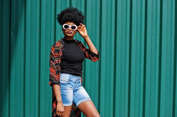 Mujer africana con pelo afro, en pantalones vaqueros cortos y gafas de sol blancas — Foto de Stock