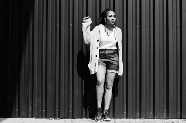 Afrikanerin mit furchteinflößenden Haaren, in Jeans-Shorts posiert gegen g — Stockfoto
