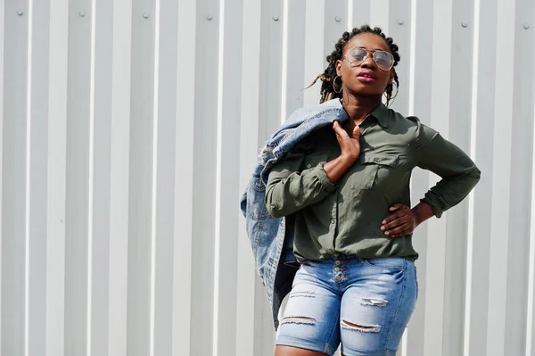 Mujer africana con rastas en el pelo, en jeans chaqueta y pantalones cortos, llevar — Foto de Stock