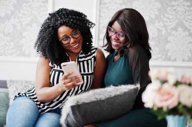 İki Afrikalı kadın arkadaş kanepede oturan gözlük giymek