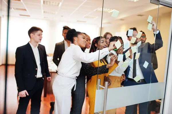 Équipe de jeunes multiculturels pointant du doigt le verre avec de la couleur — Photo