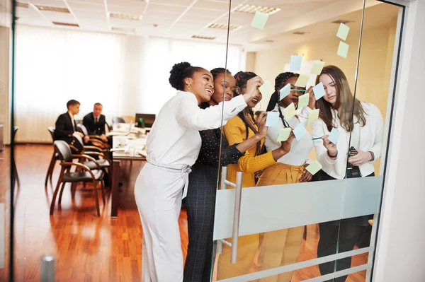 Geschäftsfrauen, die mit bunten Papierscheinen auf Glas zeigen. div. — Stockfoto