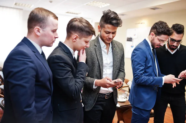 Ofiste duran ve mobil kullanan altı çok ırklı iş adamı 