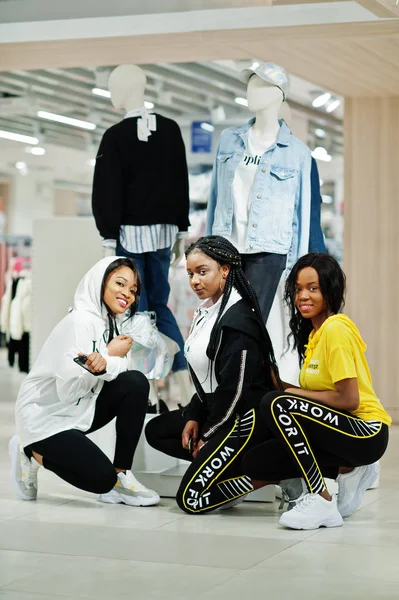 Three afican american women in tracksuits shopping at sportswear