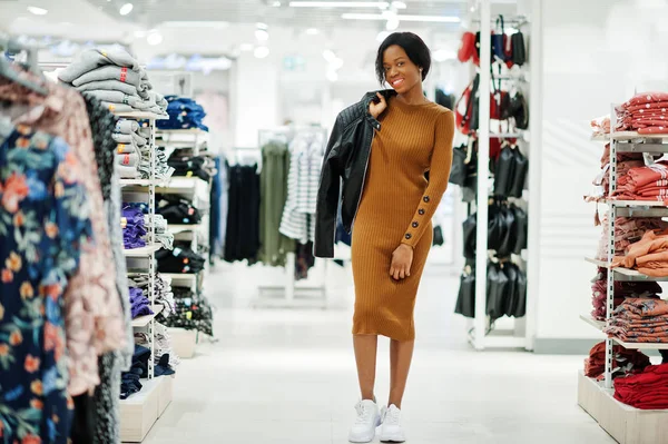 Thin african american woman in brown tunic dress and black leath