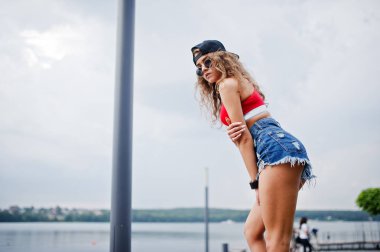 Kırmızı üst seksi model kız, kot kot şort onu kalça göstermek