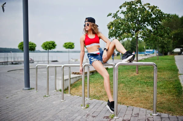 Sexy fille modèle bouclé en haut rouge, jeans short en denim, tasse sungla — Photo