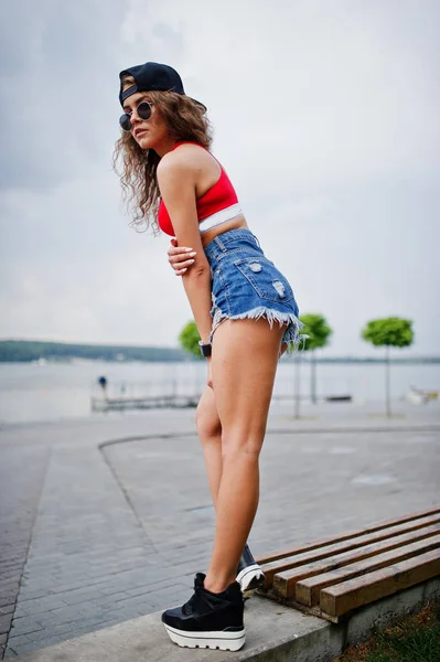 Menina modelo sexy em top vermelho, calça jeans denim shorts mostrar suas nádegas — Fotografia de Stock