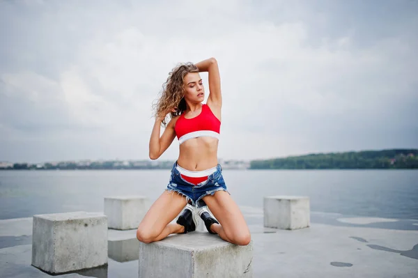 Menina modelo encaracolado Sexy em top vermelho, calça jeans jeans e sapatilha — Fotografia de Stock