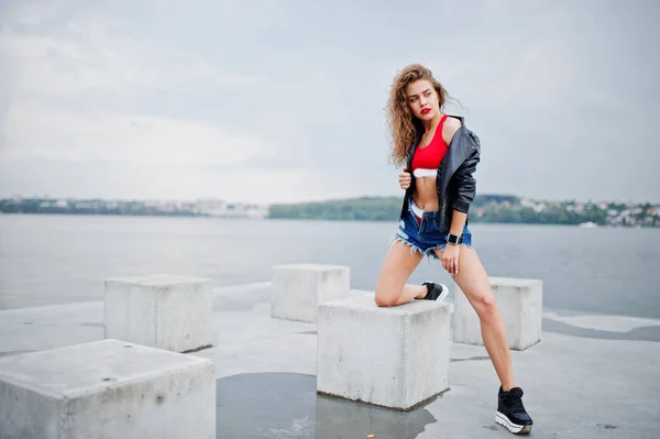 赤いトップ、ジーンズデニムショートパンツ、レザーjaのセクシーなカーリーモデルの女の子 — ストック写真