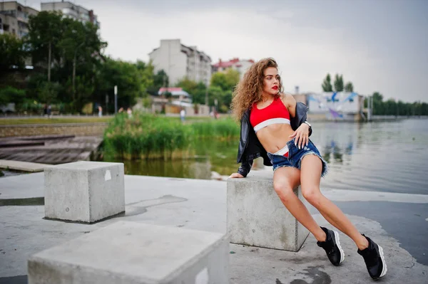 Sexy lockiges Model Mädchen in rotem Top, Jeans-Jeans-Shorts, Leder ja — Stockfoto