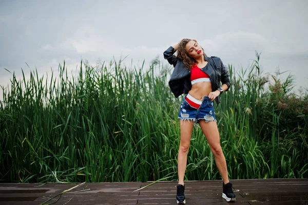 Sexy chica modelo rizado en top rojo, pantalones vaqueros vaqueros, cuero ja —  Fotos de Stock