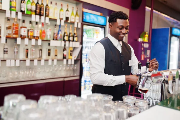 Barman afro-américain au bar versant de la bière fraîche du robinet dans — Photo