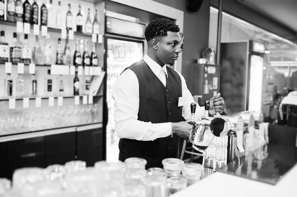 African american bartender at bar pouring from tap fresh beer in