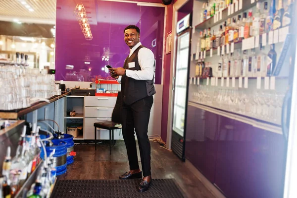 Elinde cep telefonu ile barda Afrikalı Amerikalı barmen.