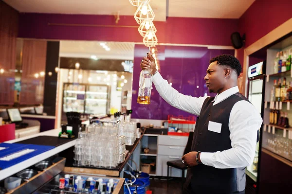 African american bartender at bar holding bootle. Alcoholic beve