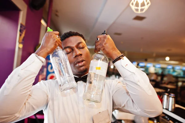 African american bartender at bar with two bottles. Alcoholic be