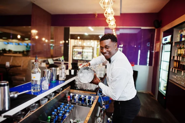 African american bartender at bar with ice bucket. Alcoholic bev