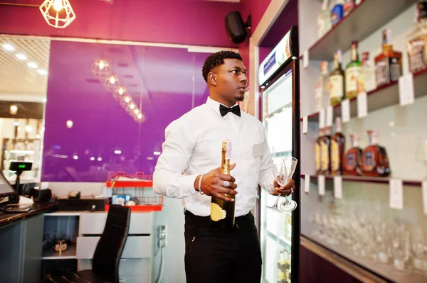 African american bartender at bar holding champagne with glasses