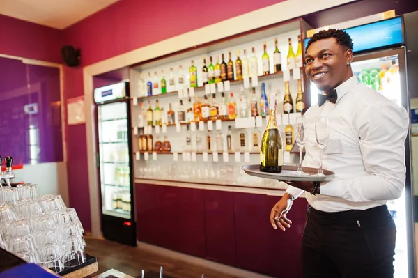 African american bartender at bar holding champagne with glasses