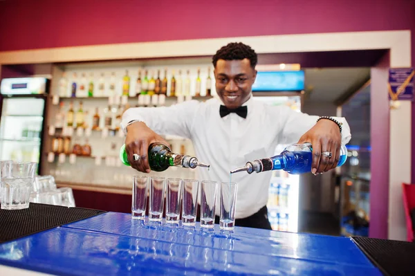 African american bartender at bar making coctails on shots. Alco