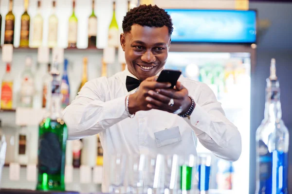 African american bartender at bar making coctails on shots and s