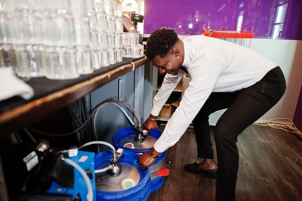 African american bartender at bar with stainless steel beer barr