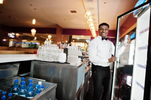African american bartender at bar taking energy drink from fridg