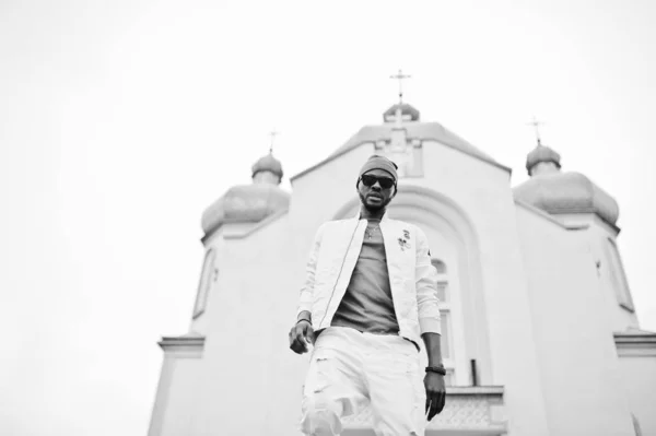 Afrikanisch-amerikanischer Mann mit Hut und Sonnenbrille steht gegen Kirche. — Stockfoto