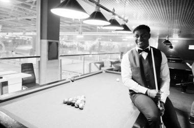 Beyaz gömlek, siyah yelek giyen yakışıklı bir Afrikalı.