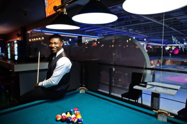 Beyaz gömlek, siyah yelek giyen yakışıklı bir Afrikalı.