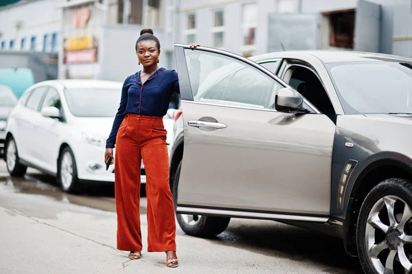 Rich business african woman in orange pants and blue shirt posed