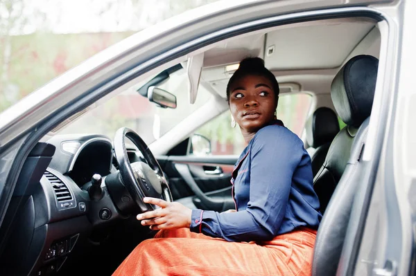 Une riche femme africaine d'affaires s'assoit sur le siège du conducteur à une voiture de sport argentée — Photo