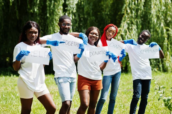 Group of happy african volunteers hold blank board in park. Afri