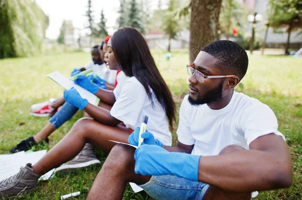 Groep van gelukkige Afrikaanse vrijwilligers zittend onder de boom in Park en — Stockfoto