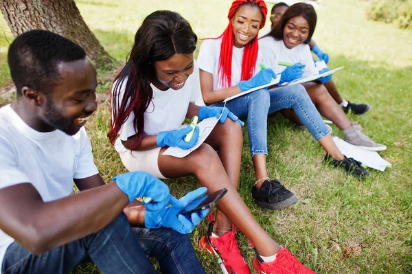 Kelompok relawan afrika bahagia duduk di bawah pohon di taman dan — Stok Foto