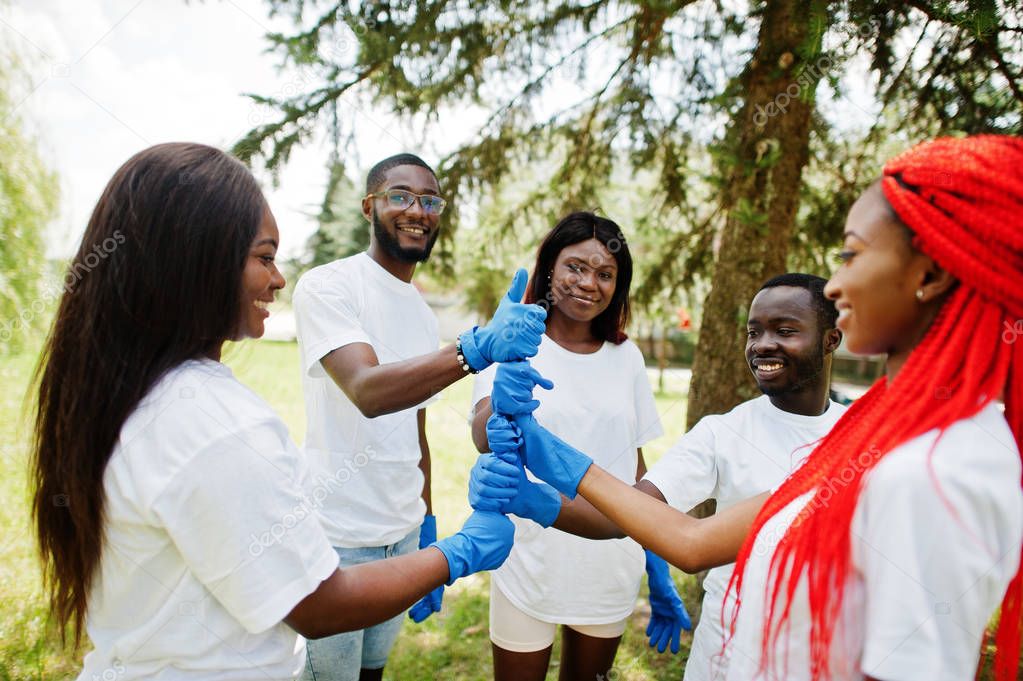 Group of happy african volunteers put hands in hands in park. Af