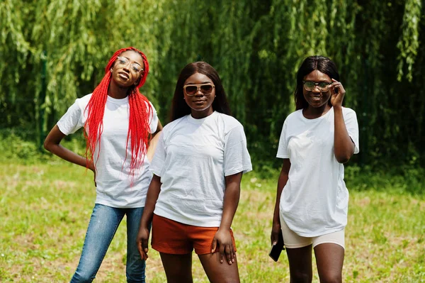 Три афро-американських жінок у парку в білих футболках. — стокове фото