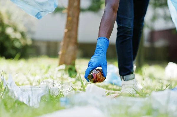 Mano de hombre afroamericano recogiendo botella en bolsas de basura — Foto de Stock