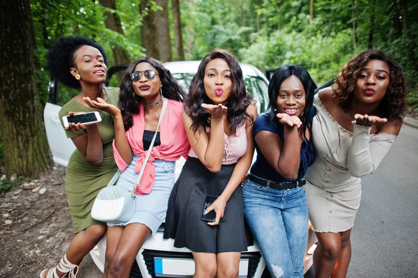 Groep van vijf gelukkig Afro-Amerikaanse meisjes zittend op een auto kap — Stockfoto