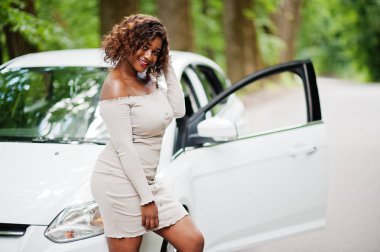 Afro-Amerikalı kadın orman yolunda beyaz otomobile karşı poz verdi.