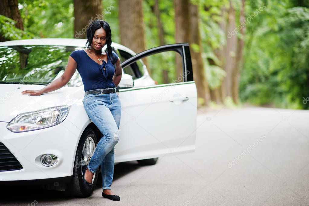 African american woman posed against white car in forest road.